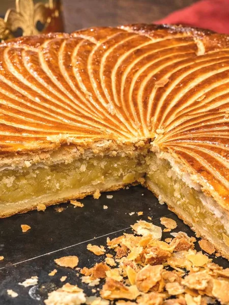 Galette des rois frangipane avec une part coupée suyr un plateau noir