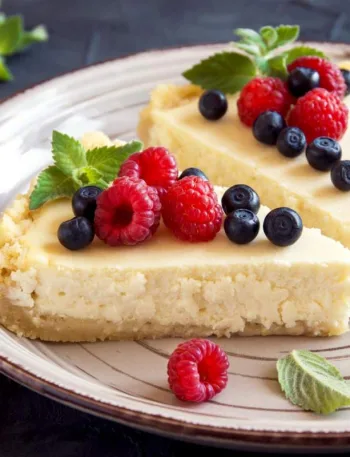 Deux parts de cheesecake avec framboises et myrtilles en déco