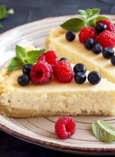 Deux parts de cheesecake avec framboises et myrtilles en déco